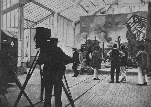 Tournage en 1903 - Photographie prise par Léancour (DR) parue dans <i>Photo Pêle-Mèle</i>, n°4, 25 juillet 1903 : « Lorsque la répétition [des artistes] a été bonne, chacun se met à son poste : les acteurs à leur place, le cinématographiste à son appareil, et, sur un signe du chef, la séance commence ». Il s'agit peut-être du tournage d'<i>Epopée napoléonienne : Napoléon Bonaparte</i> (Lucien Longuet, Pathé frères, 1903)